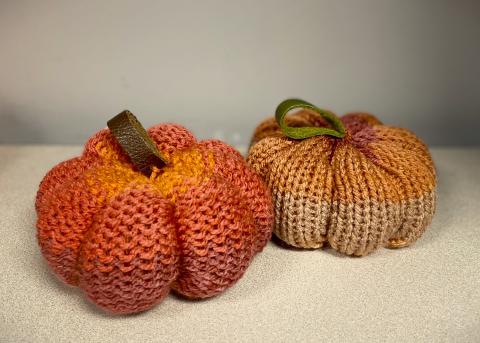 Two knit pumpkins with folded leather stems.