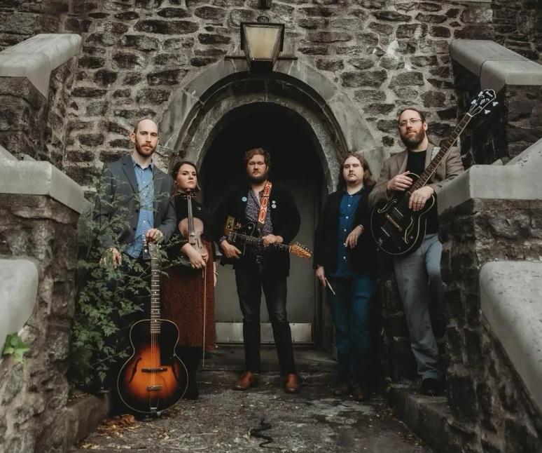 Five Sycamore Bones members stand outside with their instruments including guitar and fiddle